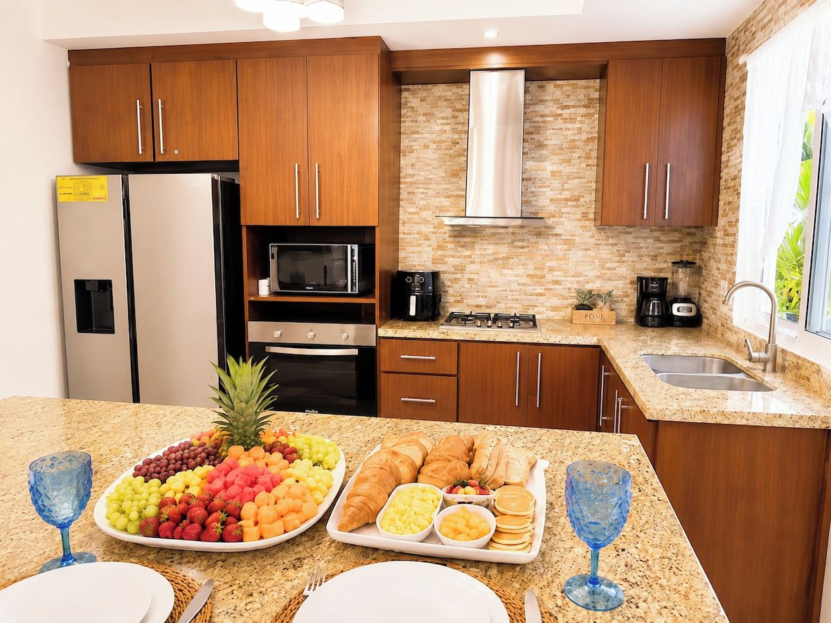 Una cocina moderna con armarios de madera, un refrigerador de acero inoxidable, un microondas y una estufa a gas.