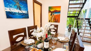 A dining area with a table set for two, featuring a bottle of wine, white flowers, and pastries. - 3 Suites | L-Shaped Pool & Caribbean Retreat (Sosúa)
