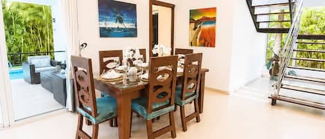 Un comedor con una mesa dispuesta para cuatro personas, rodeada de sillas con asientos acolchados.