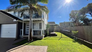 A modern two-story residential building with a balcony, a garage, and a well-maintained lawn. - Mariners in the Village (Shellharbour)
