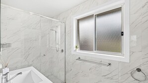 Un bagno con doccia, lavandino e finestra con vetro smerigliato.