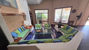 En moderne stue med en hjørnesofa, et sofabord i glas og en reol.