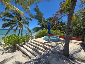 A pool area with steps leading down to the water, surrounded by palm trees and a clear view of the ocean. - Unique Seaside Retreat - with Chef & Staff (Chicxulub, Yucatan, Mexico)