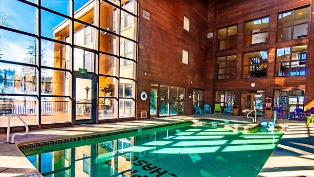Ein Innenpool mit großen Glaswänden, einem gut sichtbaren Hinweisschild und einem Poolbereich mit Liegestühlen.