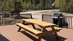 Eine Holzterrasse mit Picknicktisch und Grill.
