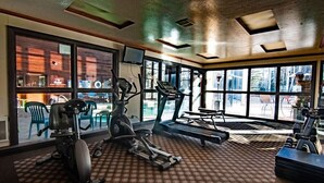 Ein Fitnessstudio mit Trainingsgeräten, großen Fenstern und Blick ins Freie.