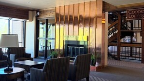 Eine Lobby mit Sitzgelegenheiten, einem Kamin und einer Treppe zu einem Lounge-Bereich.