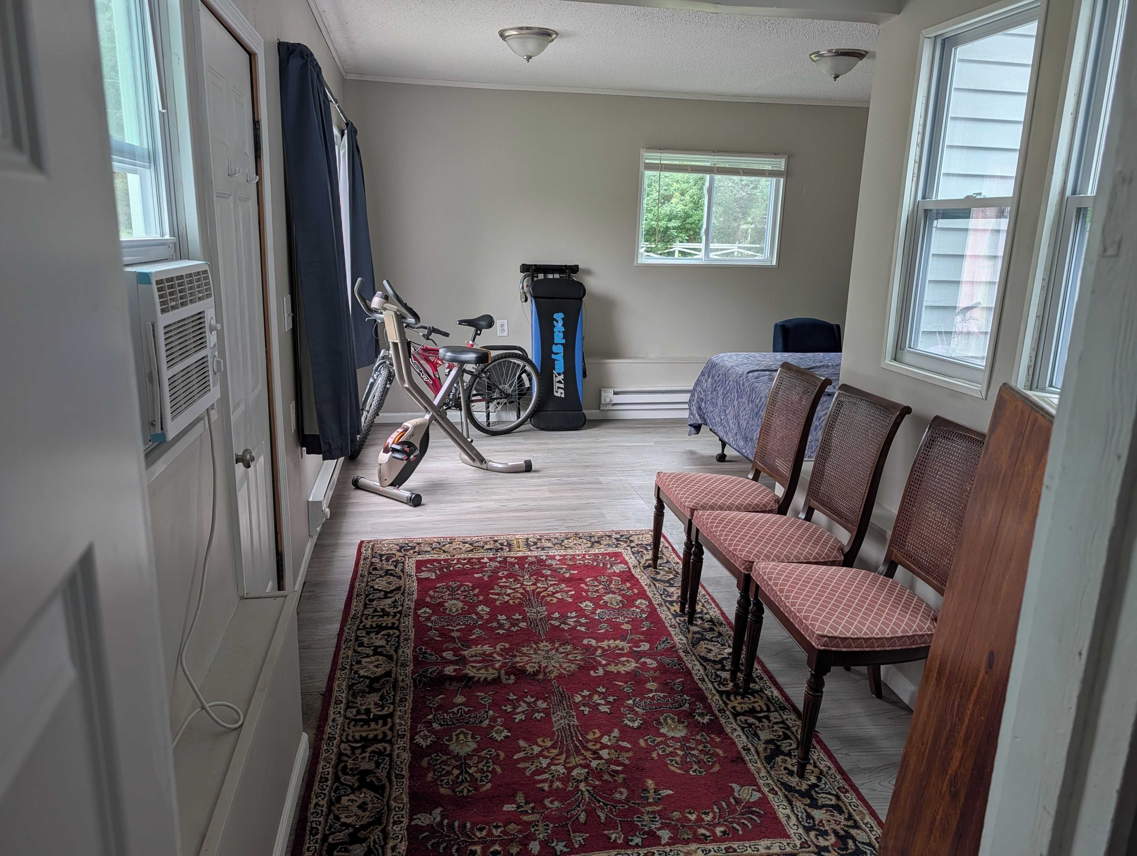 Una habitación con cama, bicicleta estática, bicicleta y una alfombra estampada.
