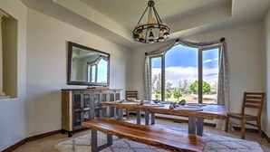 A dining area with a wooden table, benches, a chandelier, a large mirror, and a view through the windows. - Resort Style Family Fun with Guest House (Brighton)