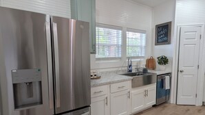 A modern kitchen with stainless steel appliances, white cabinetry, a water dispenser, and a chalkboard with a message. - Modern Historic Family Retreat House in Downtown Tupelo (Tupelo)
