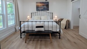 A bedroom with a bed, bedside lamps, a ceiling fan, and a painting on the wall. - Modern Historic Family Retreat House in Downtown Tupelo (Tupelo)