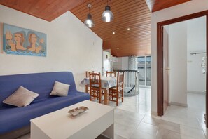 A modern living room with a blue sofa, a white coffee table, wooden dining chairs, and pendant lights. - Apartment 'Dúplex Salou' with Shared Pool, Wi-Fi and Air Conditioning (Salou)