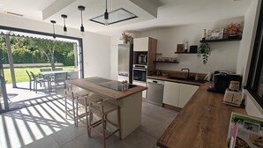A modern kitchen with a central island, built-in appliances, and a dining area with outdoor seating. - CASA NUBA - Modern villa with Jacuzzi - Between Provence & Mont Ventoux (Carpentras)