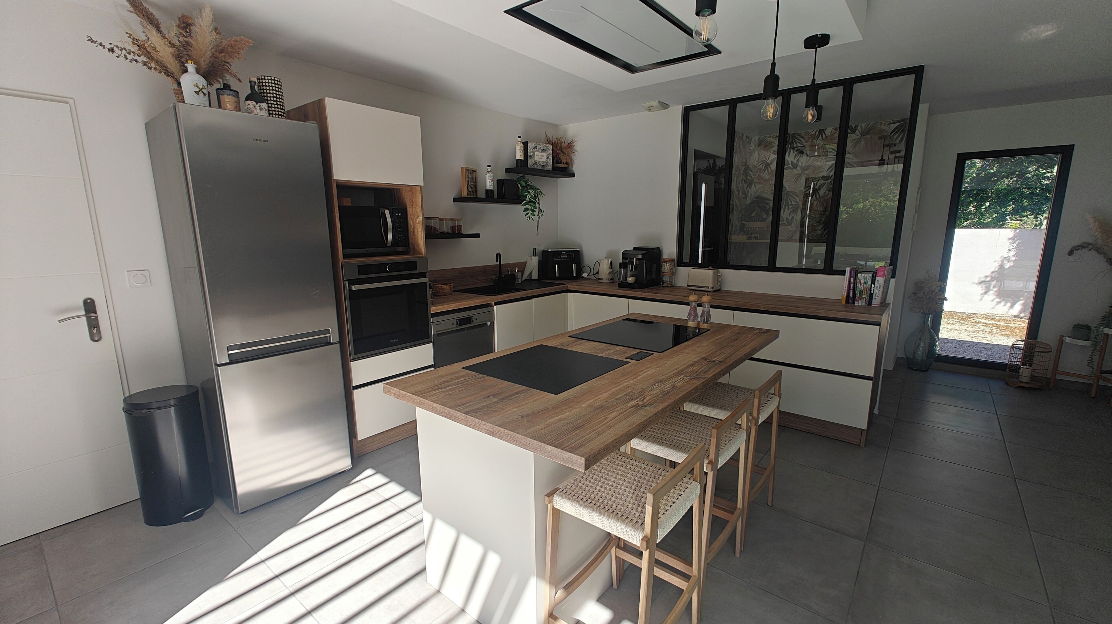 A modern kitchen with a central island, built-in appliances, and a large window.