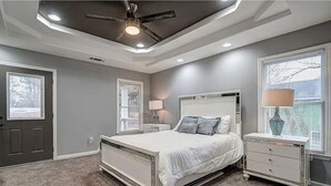 Een slaapkamer met een bed, nachtkastjes, een plafondventilator en een raam met jaloezieën.