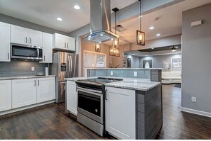 Una cocina moderna con armarios blancos, electrodomésticos de acero inoxidable y una isla central.