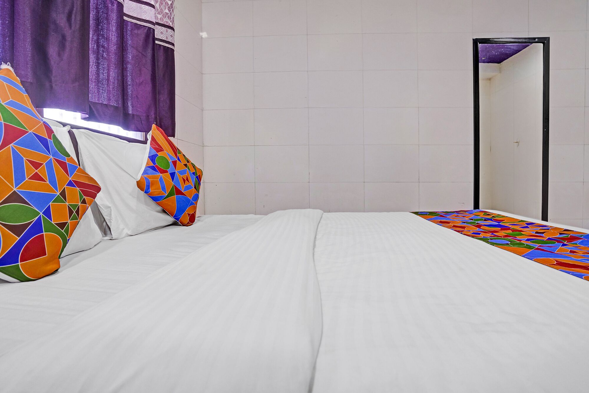 A room with a bed, a mirror, and a window with curtains.