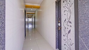 Un pasillo con paredes de azulejos blancos, una puerta tipo mármol con un panel decorativo e iluminación empotrada en el techo.