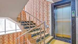 Una escalera con barandillas metálicas que lleva a un ascensor con puerta de cristal.