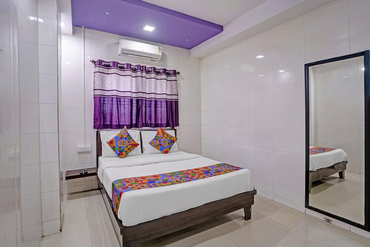 A bedroom with a bed, a mirror, and an air conditioning unit.