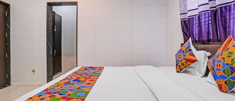 Una habitación de hotel con una cama, una puerta y un ventanal con cortinas moradas.
