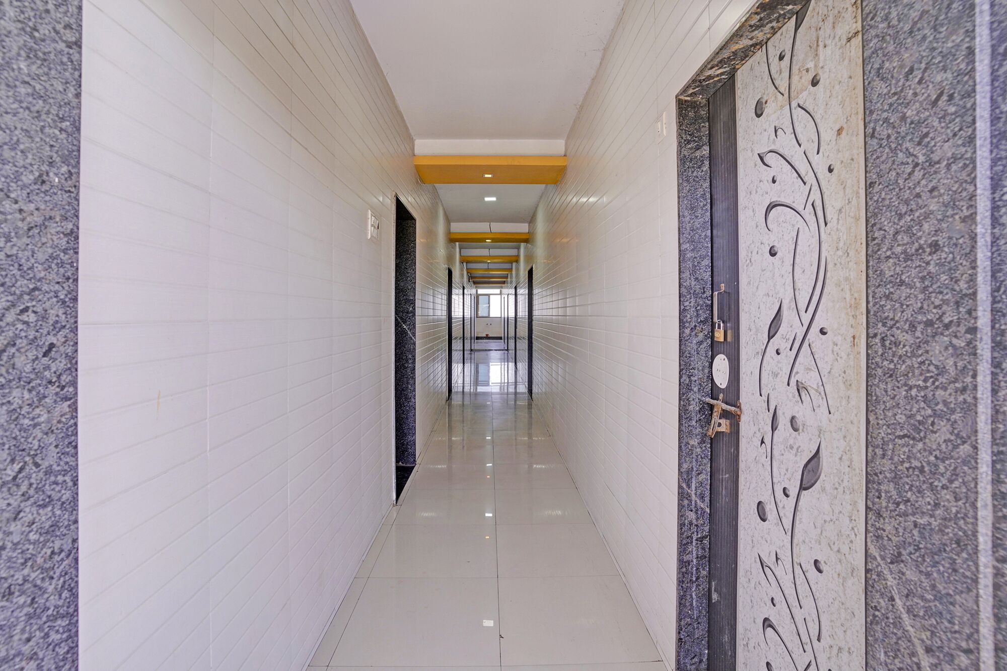 A long, narrow hallway with white tiled walls and a polished floor.