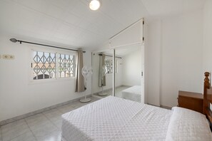 A bedroom with a bed, a mirror, a wardrobe, and a window with a view. - 'Sobreático Salou' Apartment with Shared Pool, Wi-Fi, and Air Conditioning (Salou)