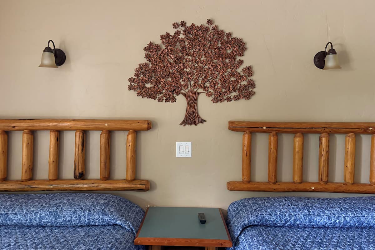 Una habitación con dos bancos de madera, una mesita y un adorno de árbol en la pared.
