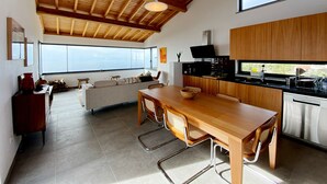 Una cucina moderna con zona pranzo, ampie finestre e soffitto alto.