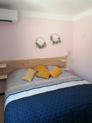 Un dormitorio con una cama, una mesita de noche con lámpara, y dos coronas decorativas en la pared.