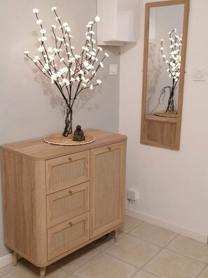 Un mueble de madera con cajones, una pequeña estatua y un jarrón con flores blancas.