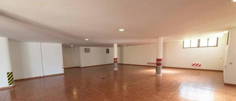 Una habitación amplia y vacía con piso de baldosas, paredes blancas e iluminación empotrada en el techo.