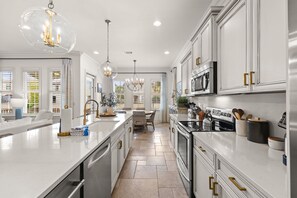 A modern kitchen with white cabinetry, stainless steel appliances, and a central island. - Luxury Resort Home w/ Two Golf Carts (Miramar Beach)