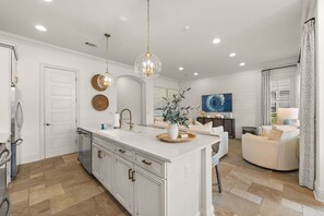 A spacious kitchen with a central island, white cabinetry, and a dining area with a round table and chairs. - Luxury Resort Home w/ Two Golf Carts (Miramar Beach)