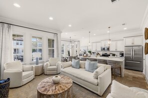 A modern kitchen with white cabinetry, stainless steel appliances, and a dining area with a round table and chairs. - Luxury Resort Home w/ Two Golf Carts (Miramar Beach)