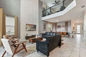Ein geräumiges Wohnzimmer mit hohen Decken, einem Essbereich und einer Treppe, die in ein Obergeschoss führt.