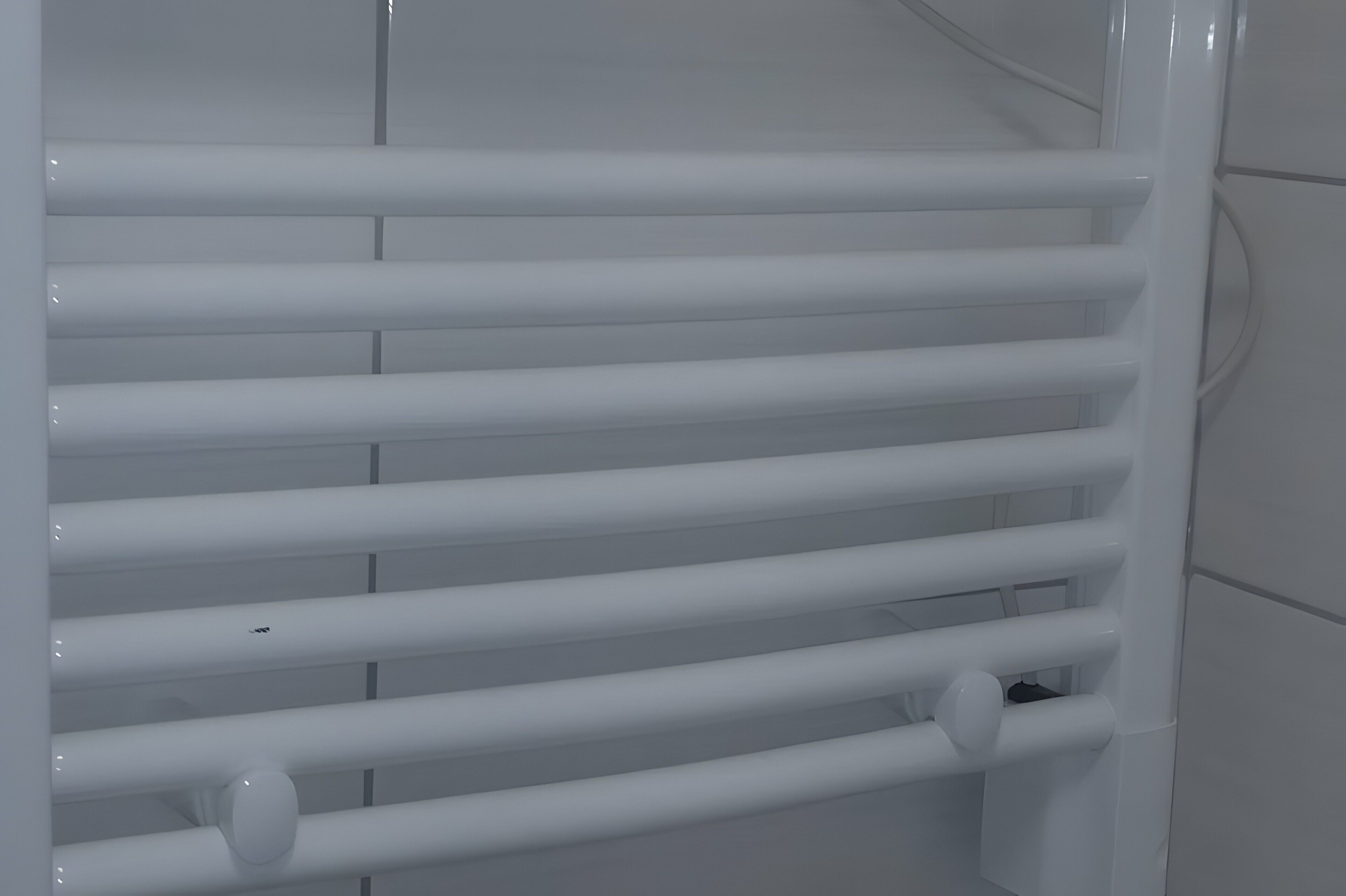 Une salle de bain moderne et blanche, avec un porte-serviettes blanc et des toilettes blanches.