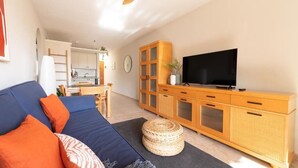 A living room with a sofa, television, wooden cabinet, and ceiling fan. - Las Olas (El Médano)