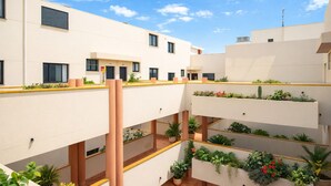 A multi-level courtyard with balconies, potted plants, and a clear sky. - Las Olas (El Médano)
