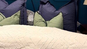 A bedroom with a bed, pillows, a painting of a field, and an abstract painting on the wall. - House Sleeps 2 With Parking (London)