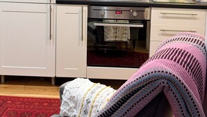A kitchen with white cabinets, a gas stove, an oven, and a red kettle on the counter. - House Sleeps 2 With Parking (London)