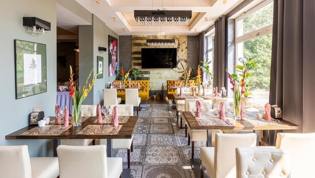 Un restaurante con varias mesas, sillas y una pantalla de televisión grande en la pared.
