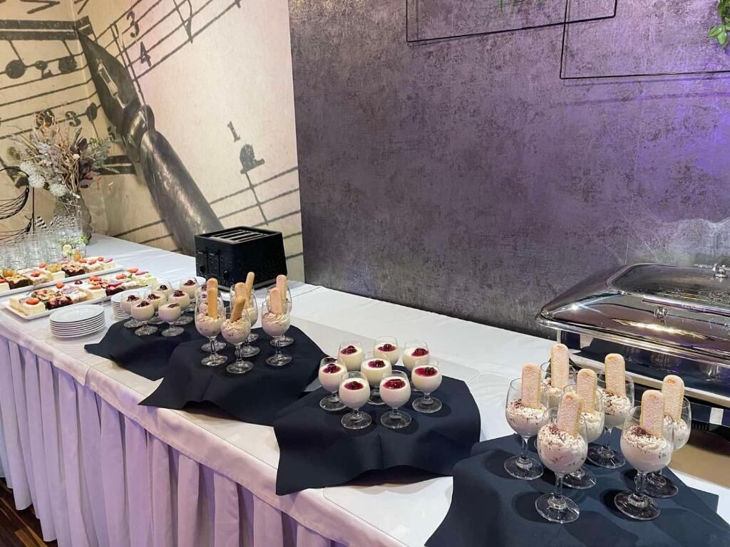 Une table de buffet proposant divers desserts et un mur décoratif sur le thème de la musique.