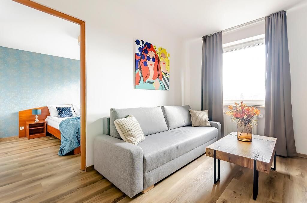 Una sala de estar moderna con un sofá gris, una mesa de centro de madera y un cuadro en la pared.