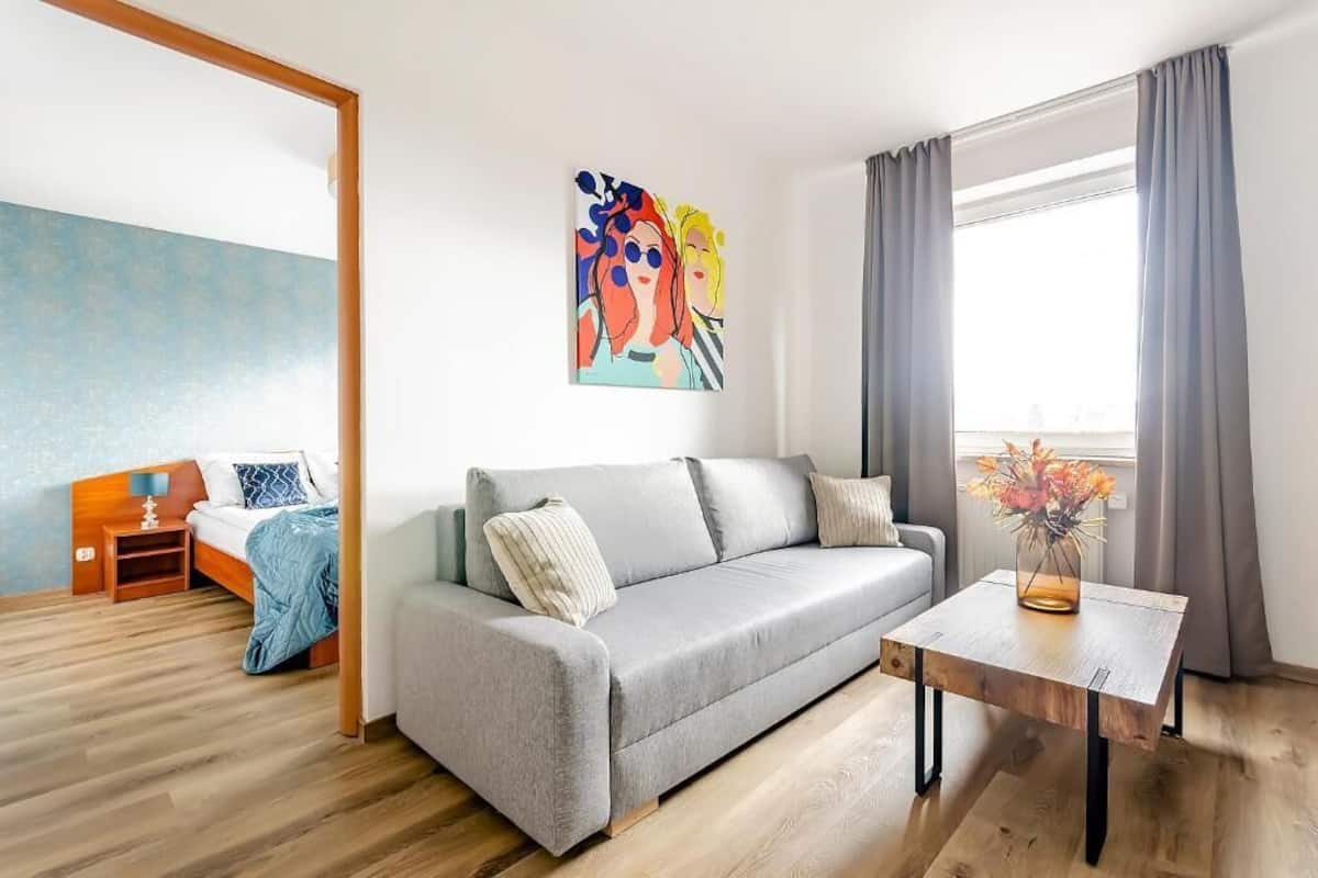A modern living room with a grey sofa, a wooden coffee table, and a painting on the wall.
