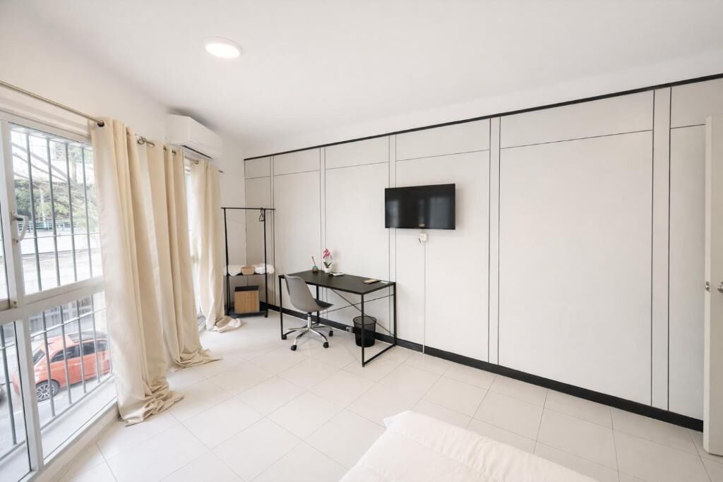 A modern bedroom with a bed, a desk, a chair, a TV, and a wardrobe.