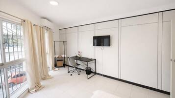 A modern bedroom with a bed, a desk, a chair, a TV, and a wardrobe.