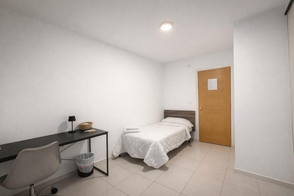 Una habitación pequeña y limpia con una cama, un escritorio y una silla.