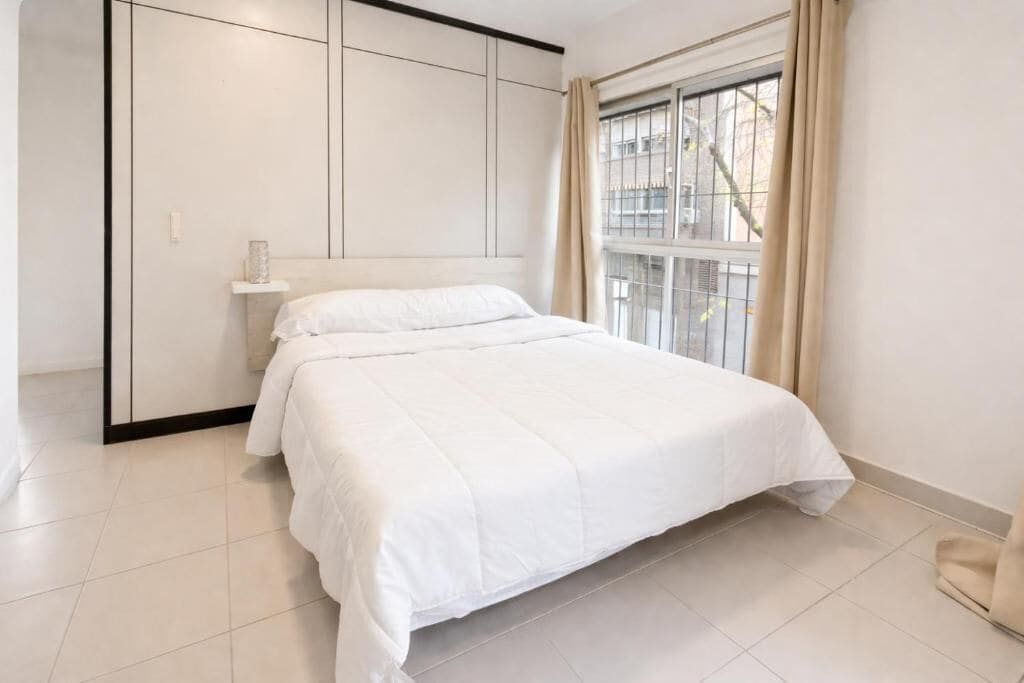 Un dormitorio con una cama, una ventana con cortinas y un armario.