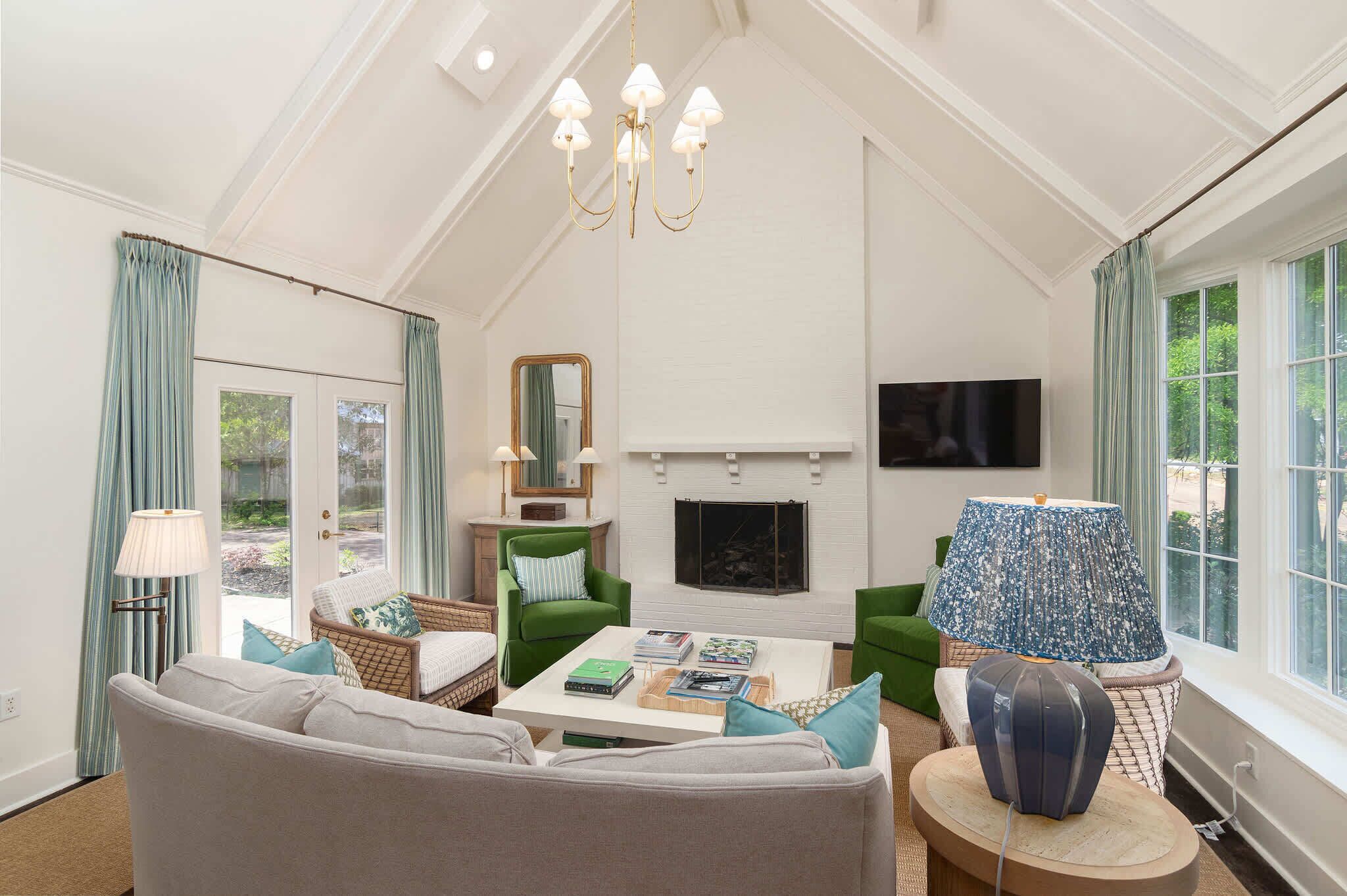 A living room with a fireplace, a television, and a chandelier.
